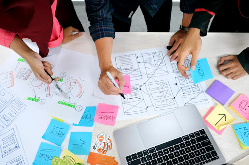 People working together over paper and sticky notes to strategize about something. 