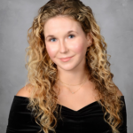 Young women posing in black dress with gray background.